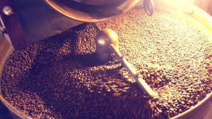35514396 - coffee beans being stirred around in a roasting machine.